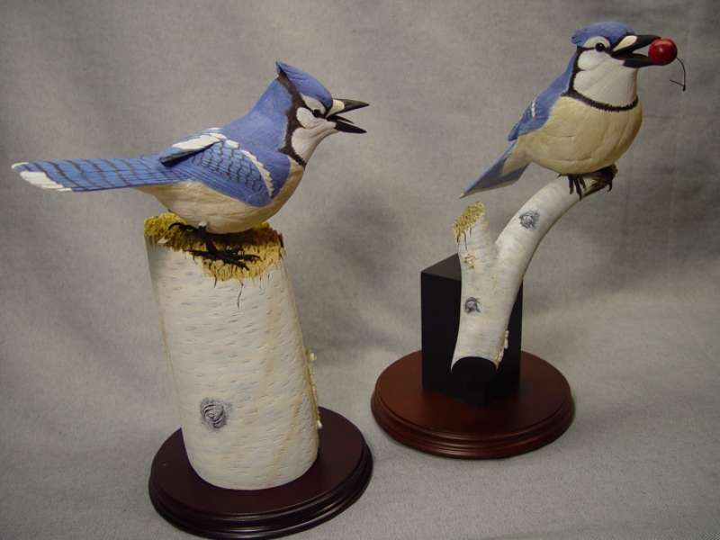 Two carved blue jays playing keep away
