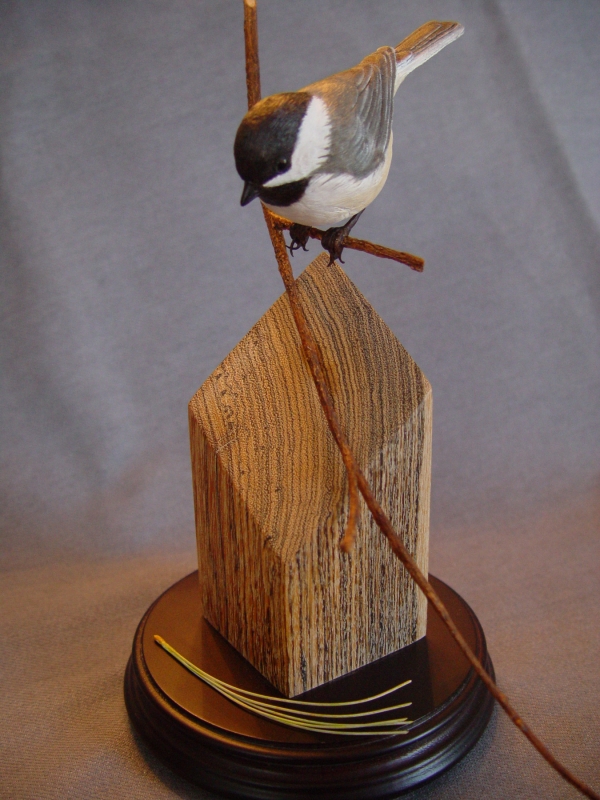 Carved chickadee with a pine needle