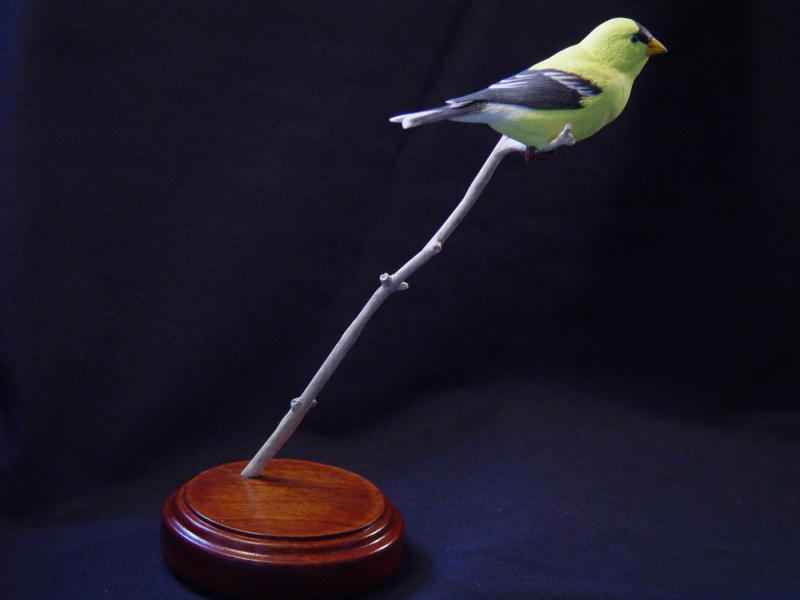 Carved goldfinch perched on a branch